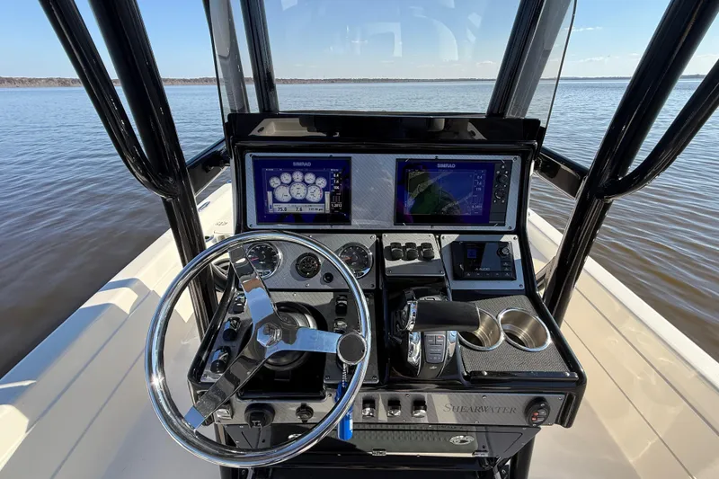 Slide: The Image of 2018 ShearWater 23LTZ boat dashboard with steering wheel and navigation screens. - 9