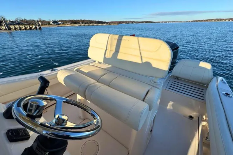 Slide: The Image of 2024 Grady-White Fisherman 216 boat interior with steering wheel and seating, on calm water. - 18