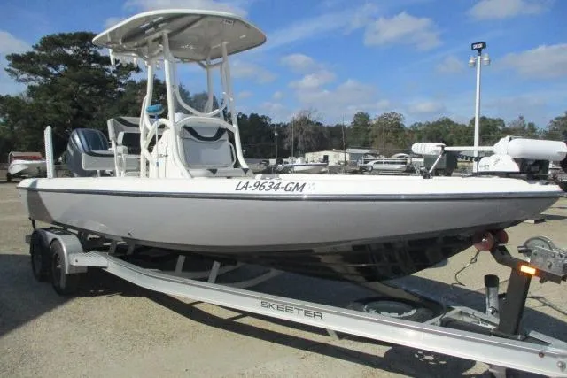 Slide: The Image of 2021 Skeeter SX240 boat on trailer, parked outdoors under blue sky. - 2