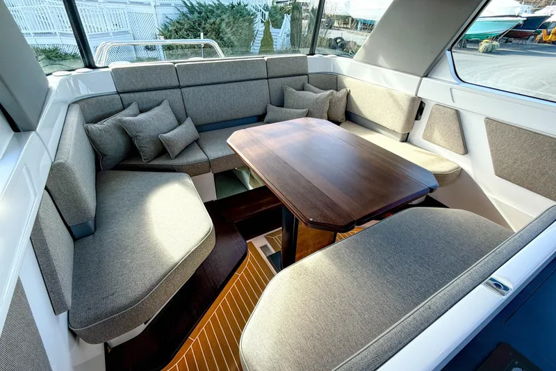 Slide: The Image of 2024 Axopar 45 XC Cross Cabin interior with cozy seating and wooden table. - 10