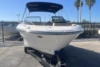 Slide: The Image of 2024 Sea Ray SPX 210 Outboard boat with canopy, parked on trailer, sunny day. - 2