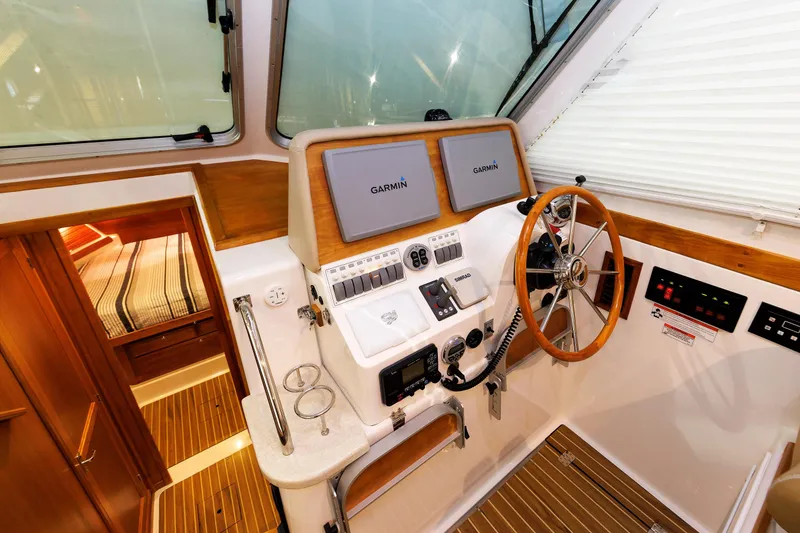 Slide: The Image of 2011 Back Cove 37 boat helm with Garmin navigation, wooden accents, and cozy cabin view. - 30
