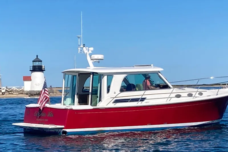 Slide: The Image of 2011 Back Cove 37 boat with red hull near a lighthouse on a sunny day. - 45