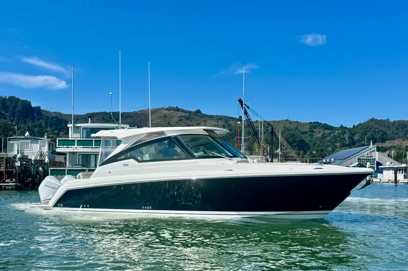 The Image of 2026 Tiara Yachts 34 LX cruising on a sunny day near a marina. - 0