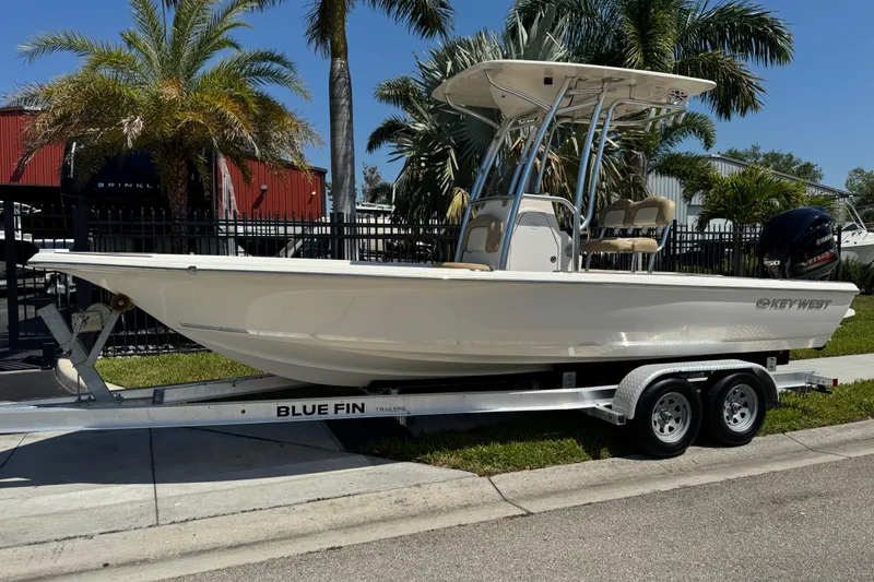 The Image of 2019 Key West 230 Bay Reef boat on Blue Fin trailer, parked near palm trees. - 1