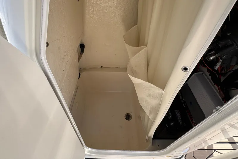 Slide: The Image of 2019 Key West 230 Bay Reef boat storage compartment with curtain and visible battery. - 95