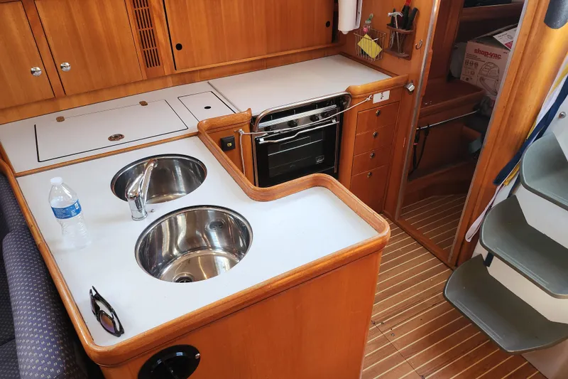 Slide: The Image of 2005 Elan 40 yacht kitchen with dual sinks, stove, and wooden cabinetry. - 17