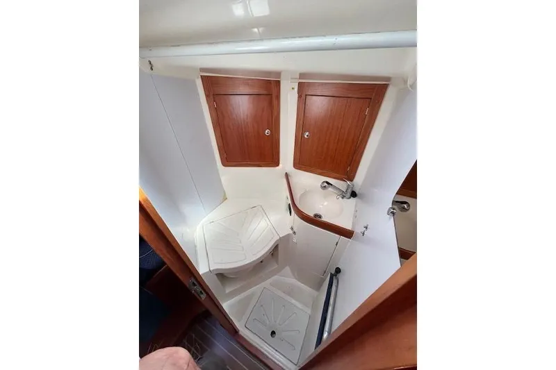 Slide: The Image of Compact bathroom in a 2005 Elan 40 yacht with wooden cabinets and a small sink. - 27