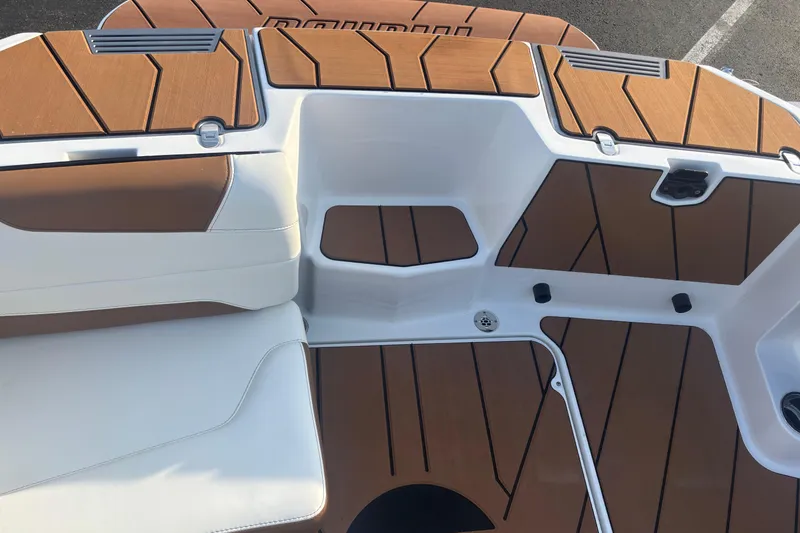 Slide: The Image of 2025 Malibu Response TXi boat interior with brown and white seating and deck design. - 15