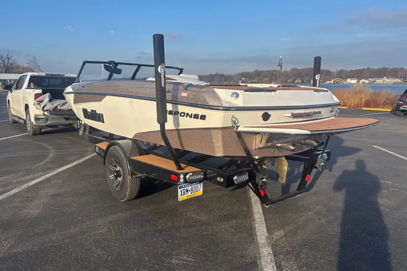 Slide: The Image of 2025 Malibu Response TXi boat on trailer, parked near a lake under clear skies. - 3
