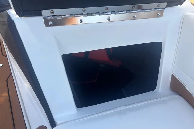 Slide: The Image of 2025 Malibu Response TXi boat storage compartment with white and brown seating. - 8