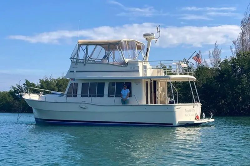 Slide: The Image of 2007 Mainship 400 Trawler cruising on a serene waterway with clear skies. - 1