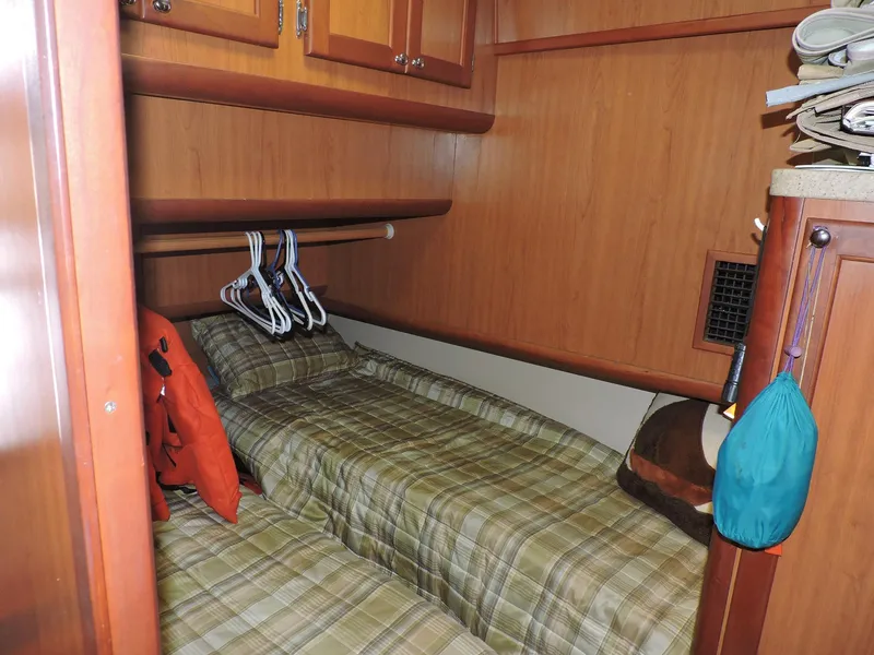 Slide: The Image of 2007 Mainship 400 Trawler cabin with plaid bedding and wooden cabinetry. - 10