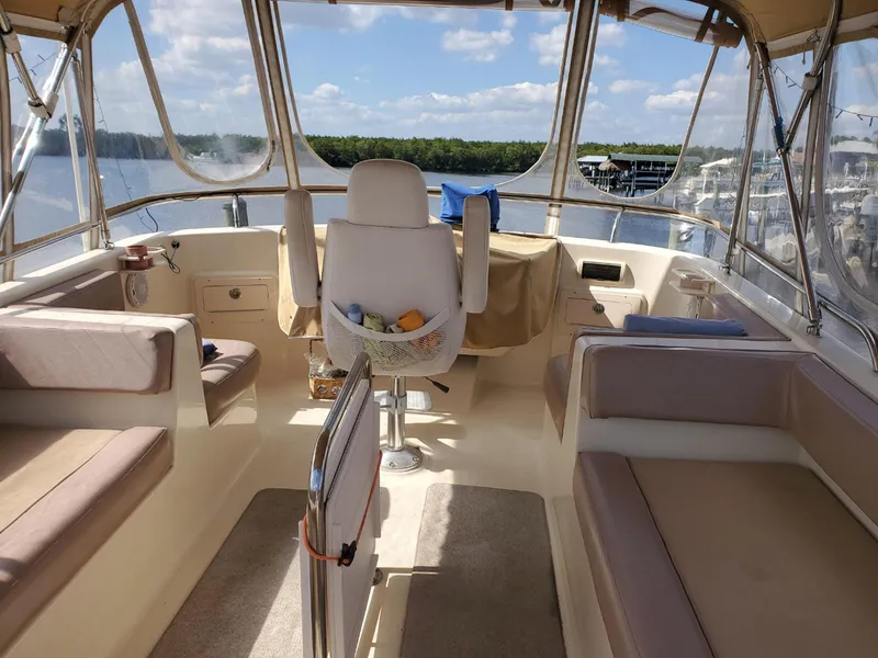 Slide: The Image of 2007 Mainship 400 Trawler interior with seating and helm, overlooking a scenic water view. - 15