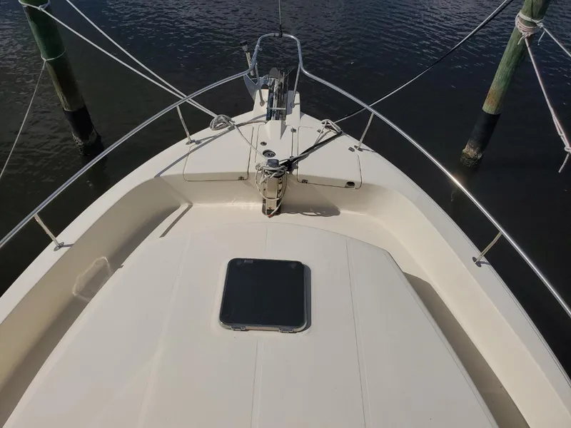 Slide: The Image of 2007 Mainship 400 Trawler bow view with anchor and railing, docked on calm water. - 19