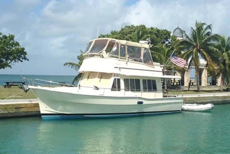 Slide: The Image of 2007 Mainship 400 Trawler docked by palm trees and clear water. - 2