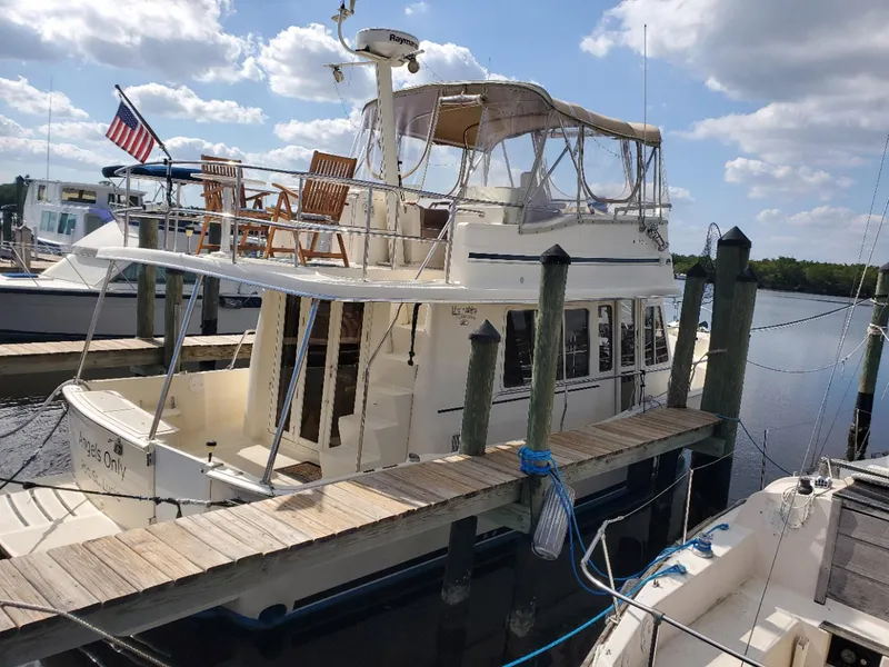 Slide: The Image of 2007 Mainship 400 Trawler docked, featuring upper deck seating and American flag. - 3