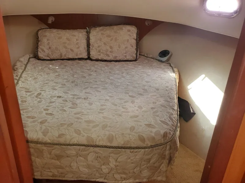 Slide: The Image of 2007 Mainship 400 Trawler cabin with a cozy bed and decorative pillows. - 8