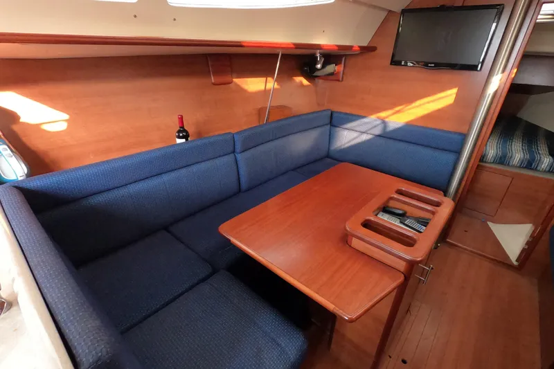 Slide: The Image of Interior of 2013 Marlow-Hunter e33 sailboat with blue seating and wooden table. - 34