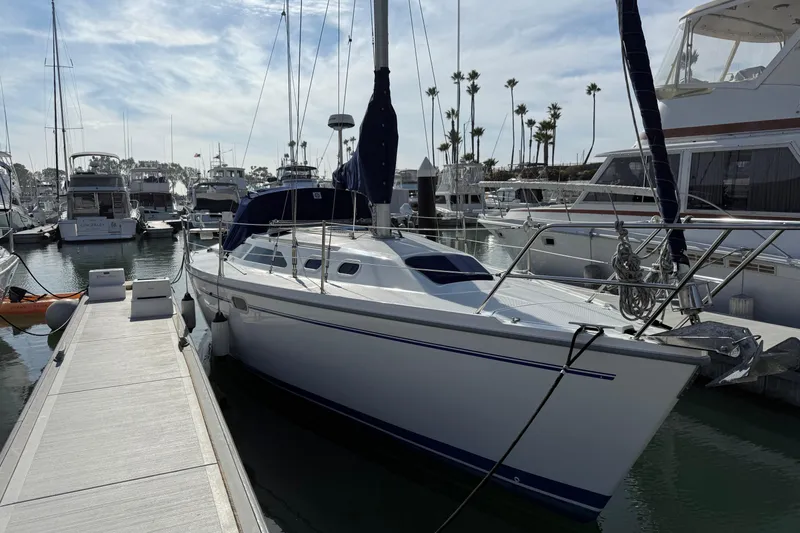 Slide: The Image of Catalina 320 sailboat docked in marina, surrounded by other boats, clear sky. - 1
