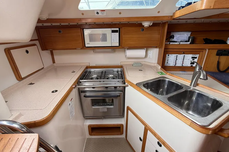 Slide: The Image of Compact kitchen in a 2000 Catalina 320 sailboat with stove, microwave, and dual sinks. - 10