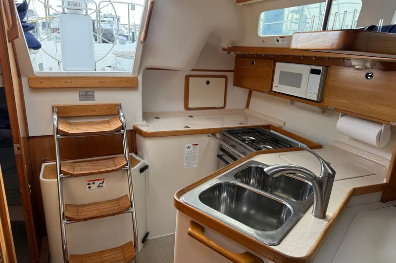 Slide: The Image of Interior of a 2000 Catalina 320 sailboat kitchen with sink, stove, and microwave. - 11
