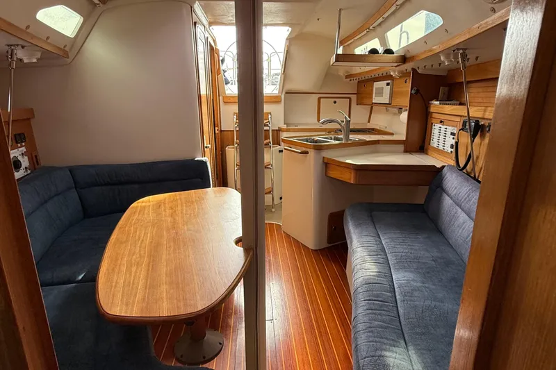Slide: The Image of Interior of a 2000 Catalina 320 sailboat with wood accents and blue seating. - 14