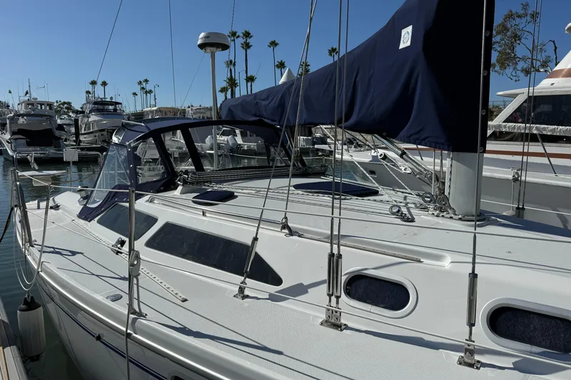 Slide: The Image of 2000 Catalina 320 sailboat docked in marina, featuring sleek design and blue sail cover. - 2