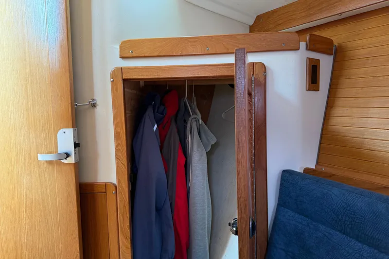 Slide: The Image of Interior of 2000 Catalina 320 sailboat showing wooden closet with hanging clothes. - 21