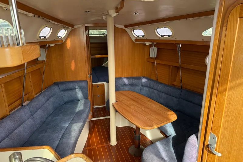 Slide: The Image of Interior of a 2000 Catalina 320 sailboat with wooden furnishings and blue seating. - 9
