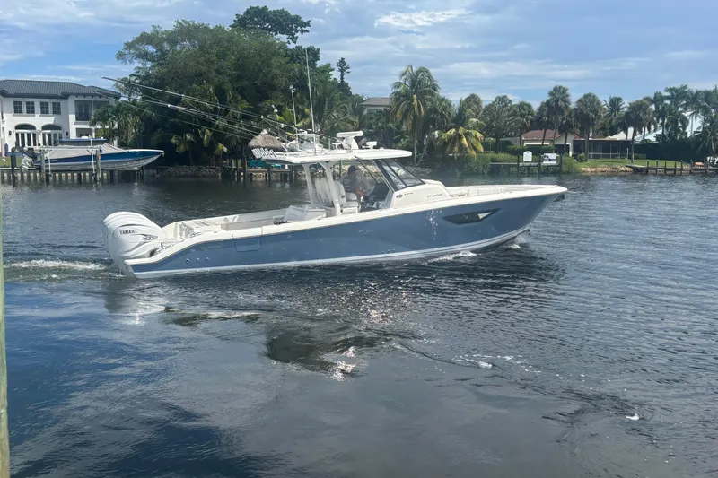 The Image of 2021 Pursuit S 378 Sport boat cruising on a scenic waterway with palm trees. - 1