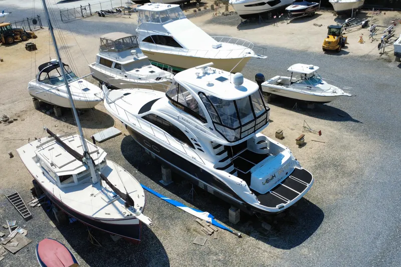 Slide: The Image of 2007 Sea Ray 52 Sedan Bridge yacht in a boatyard, surrounded by various vessels. - 27