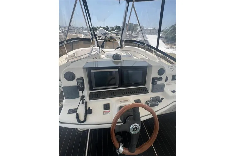 Slide: The Image of 2007 Sea Ray 52 Sedan Bridge helm with dual screens and wooden steering wheel. - 32