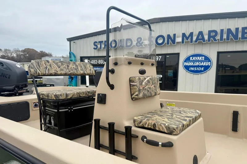 Slide: The Image of 2026 Carolina Skiff E21 DLX CC boat with camouflage seating at a marine dealership. - 14