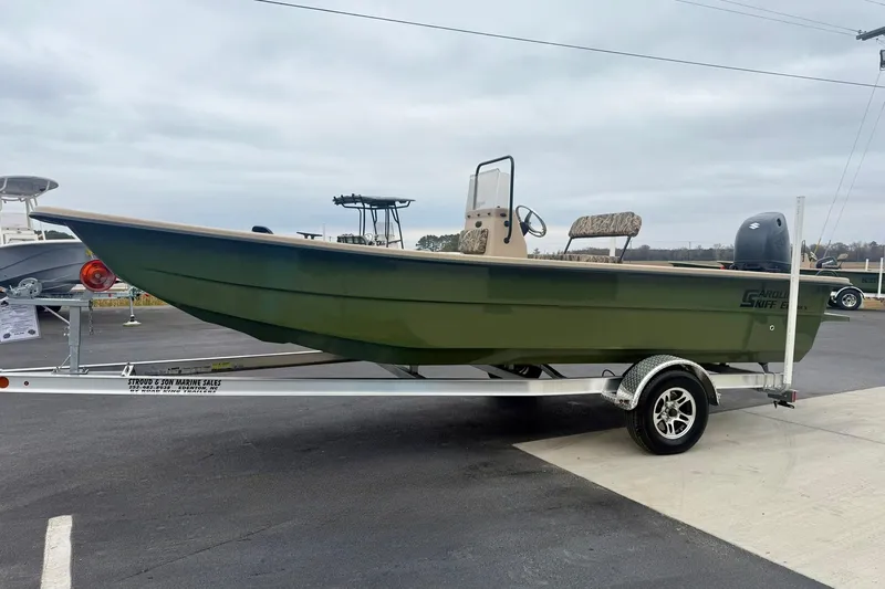 Slide: The Image of 2026 Carolina Skiff E21 DLX CC boat on trailer, green hull, parked outdoors. - 5