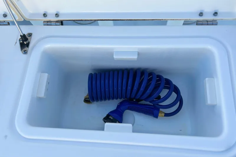 Slide: The Image of Storage compartment with blue coiled hose in 2017 Key West Billistic 281 Center Console boat. - 14