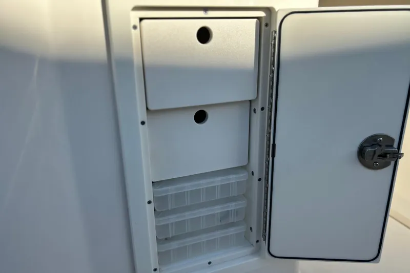 Slide: The Image of 2017 Key West Billistic 281 Center Console storage compartment with open door and organized shelves. - 21