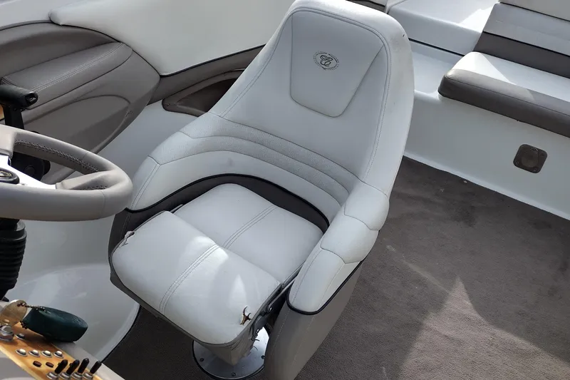 Slide: The Image of Captain's seat in a 2000 Cobalt 246 boat, featuring white upholstery and steering wheel. - 18