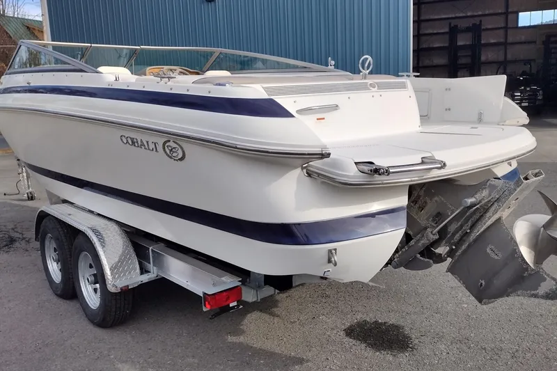 Slide: The Image of 2000 Cobalt 246 boat on trailer, parked outdoors near a blue building. - 7