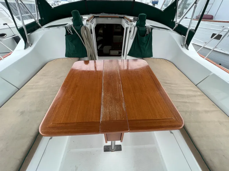 Slide: The Image of 2004 Beneteau 473 yacht cockpit with wooden table and cushioned seating. - 15