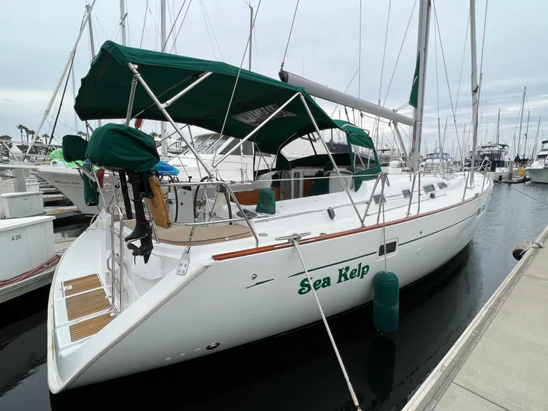 Slide: The Image of 2004 Beneteau 473 sailboat docked, featuring green canopy and "Sea Kelp" name. - 2