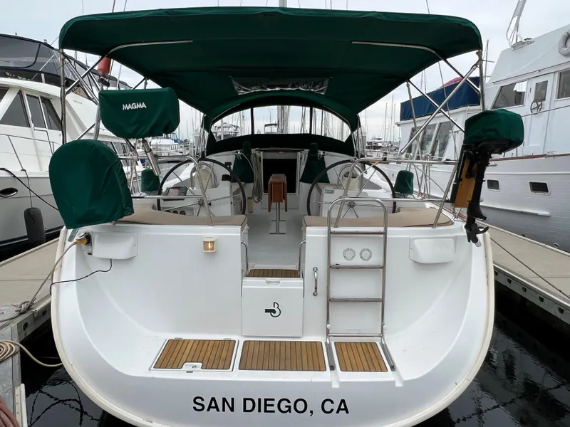 Slide: The Image of 2004 Beneteau 473 sailboat docked in San Diego marina, featuring green canopy and dual steering wheels. - 3