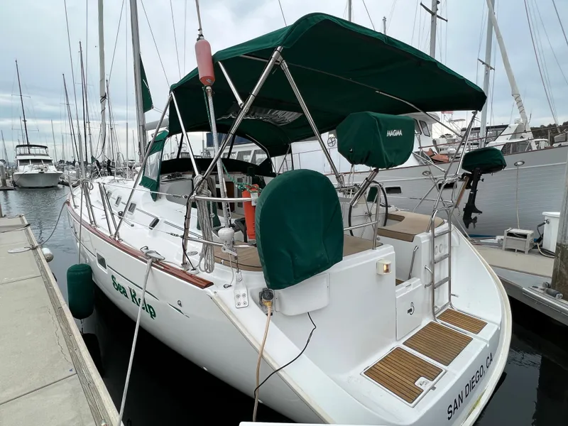 Slide: The Image of 2004 Beneteau 473 sailboat docked, featuring green covers and canopy, in a marina setting. - 4