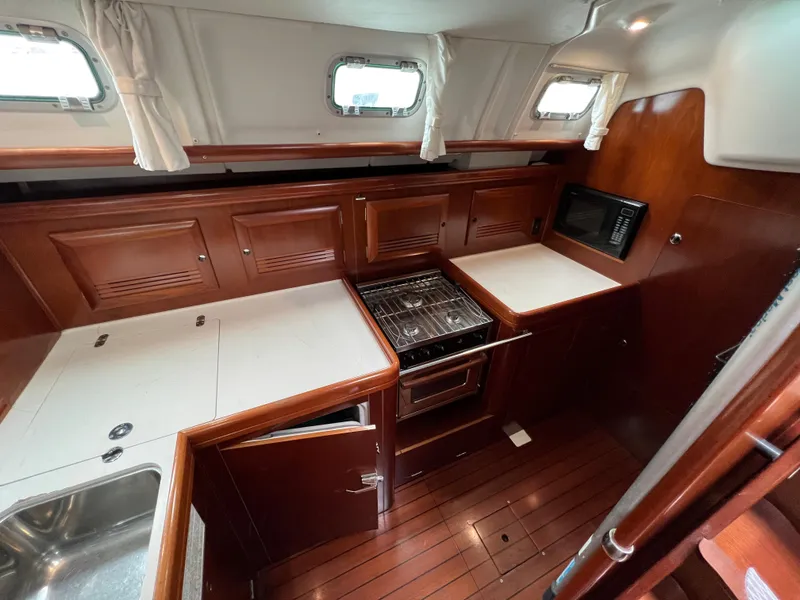 Slide: The Image of 2004 Beneteau 473 yacht kitchen with wood cabinetry, stove, and sink. - 42