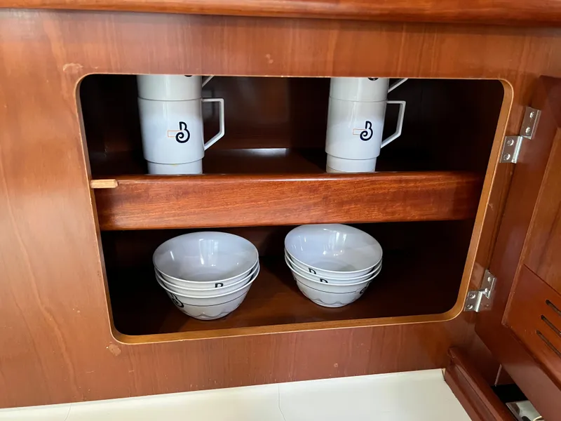 Slide: The Image of Wooden cabinet with stacked mugs and bowls on a Beneteau 473 yacht, 2004 model. - 48