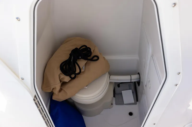 Slide: The Image of Interior of 2023 Edgewater 245CC boat showing compact marine toilet and storage items. - 11