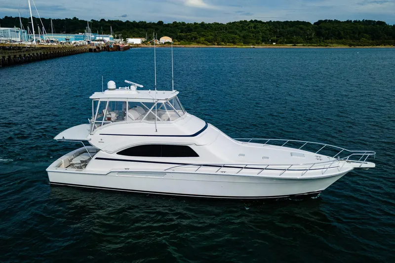 The Image of 2008 Bertram 570 yacht cruising on calm waters near a marina. - 0