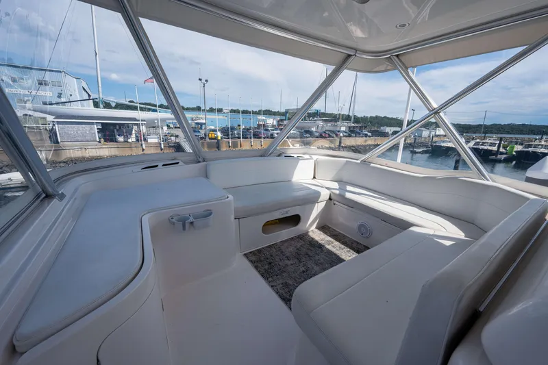 Slide: The Image of Interior view of a 2008 Bertram 570 yacht with white seating and marina backdrop. - 12