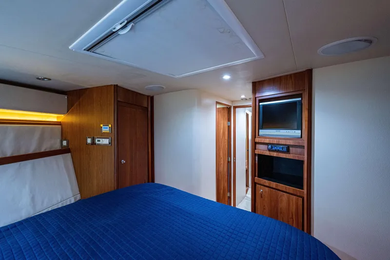 Slide: The Image of Luxurious 2008 Bertram 570 yacht cabin with wood paneling and blue bedding. - 41