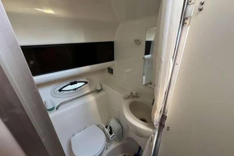 Slide: The Image of 2007 Bayliner 285 boat bathroom with toilet, sink, and porthole window. - 16